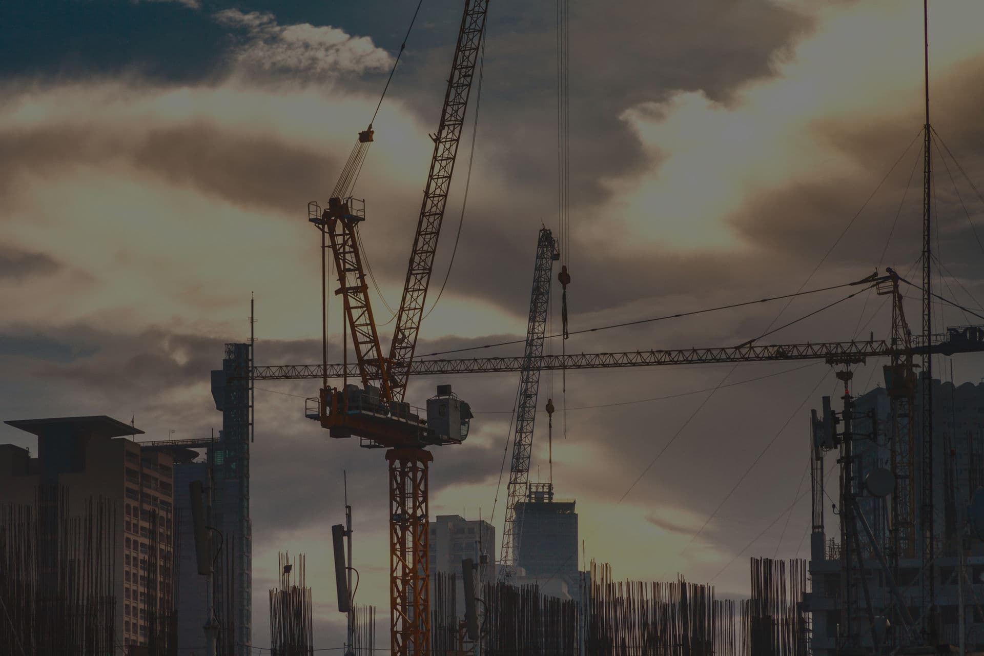 Tower cranes over a city construction site at sunset